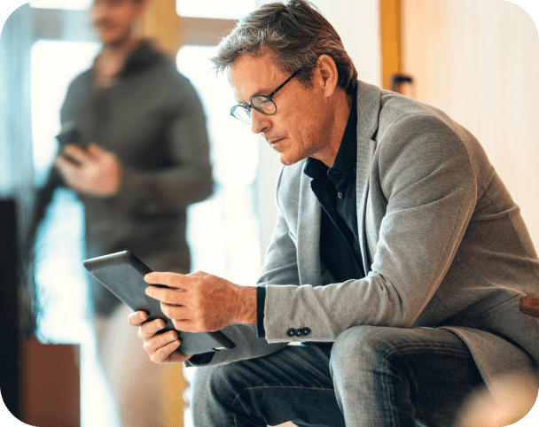 Man sitting and hunched over looking at smart tablet