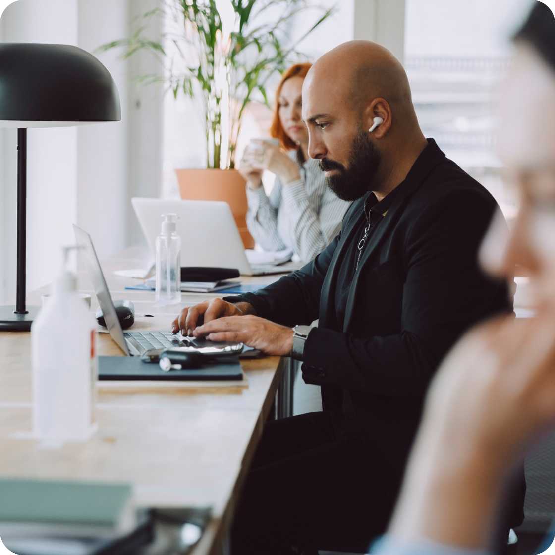 Man and woman on laptops at a conference table.