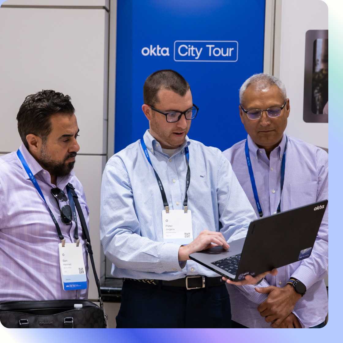 Image of three employees chatting and looking at laptop at Okta City Tours