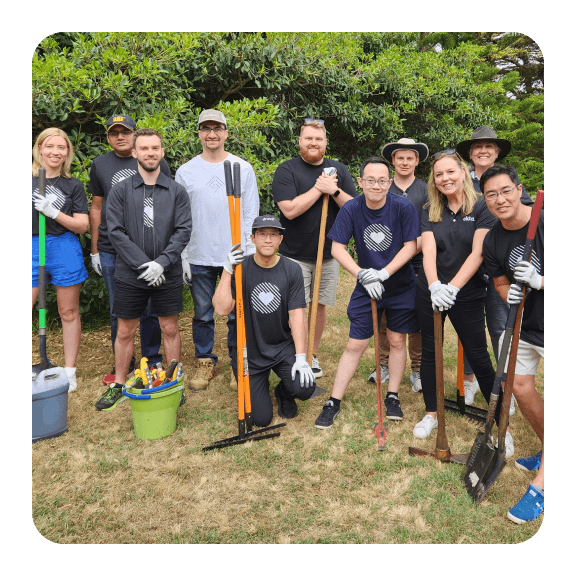 Image of Okta employees posing with rakes and shovels in a park