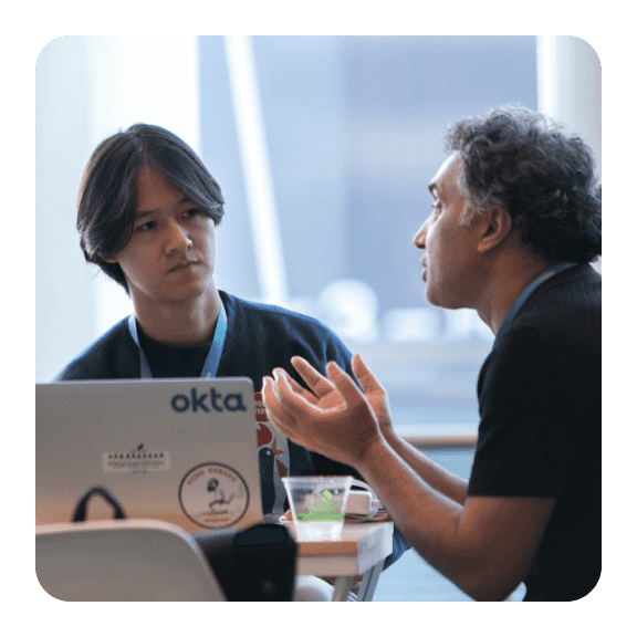 Image of two men chatting with laptop out on desk