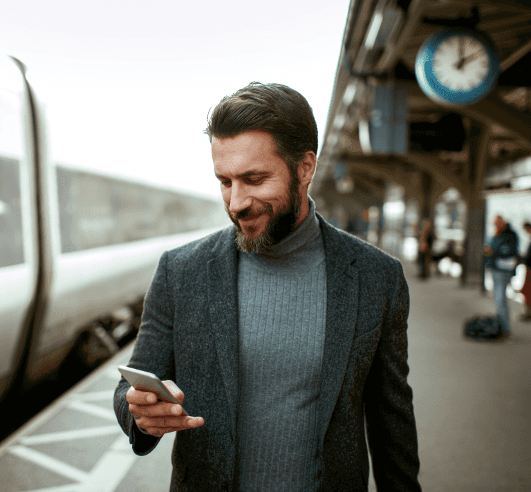 A man smiling while glancing down at his phone. 