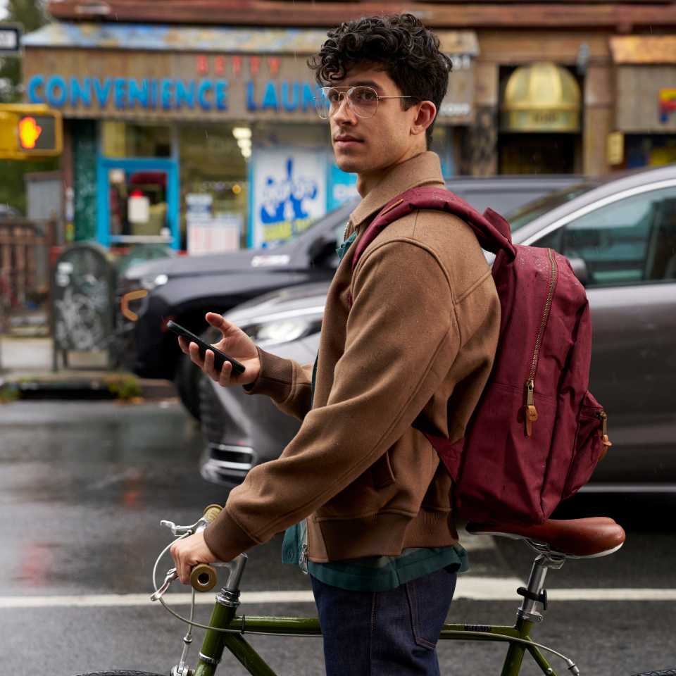 Image of man standing on city street with bike and smartphone in hand