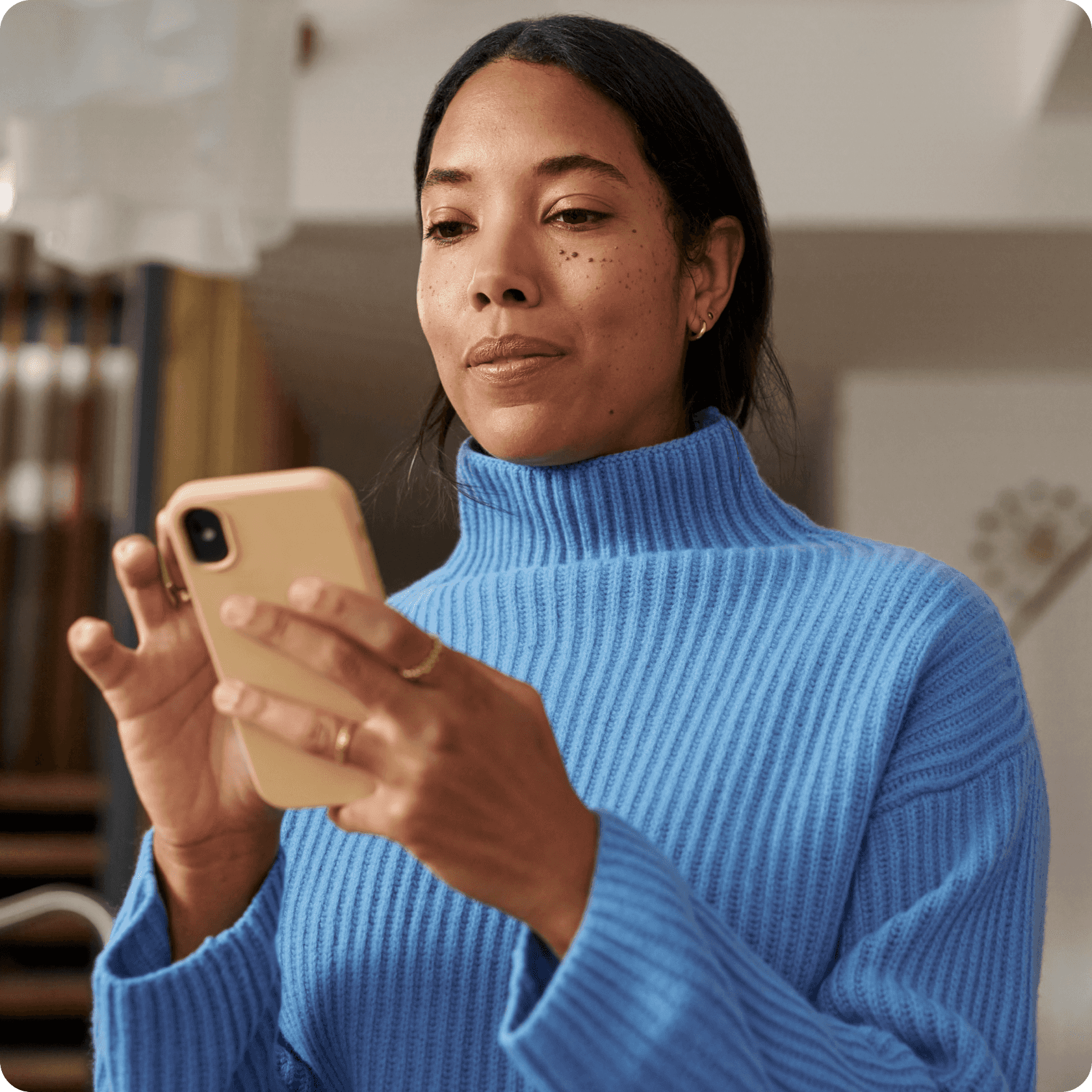 Woman wearing blue turtleneck blouse using smartphone