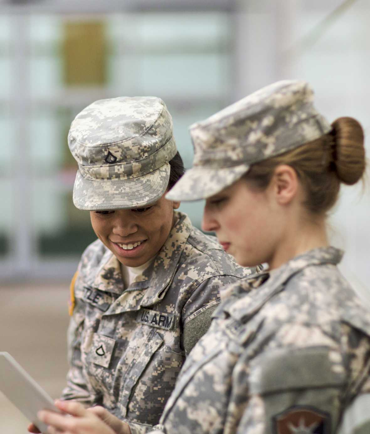 Two women in professional clothes, taking and smiling while walking down government building steps.