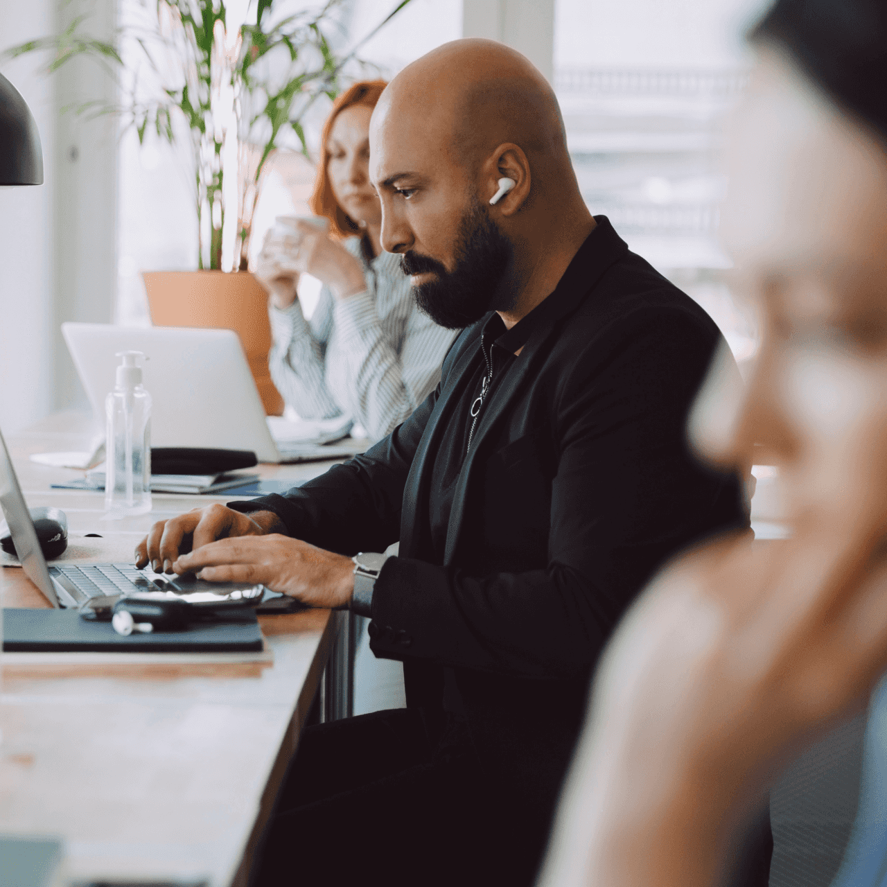 Image of a man sitting at the computer in an office with his headsets.