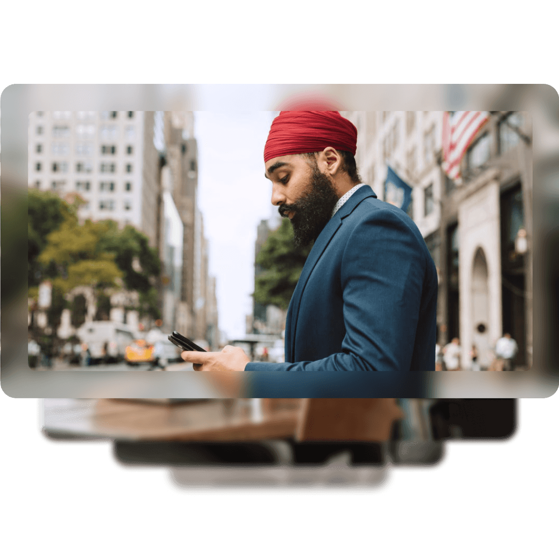 An image of a man walking through the city holding his phone as he crosses the street.