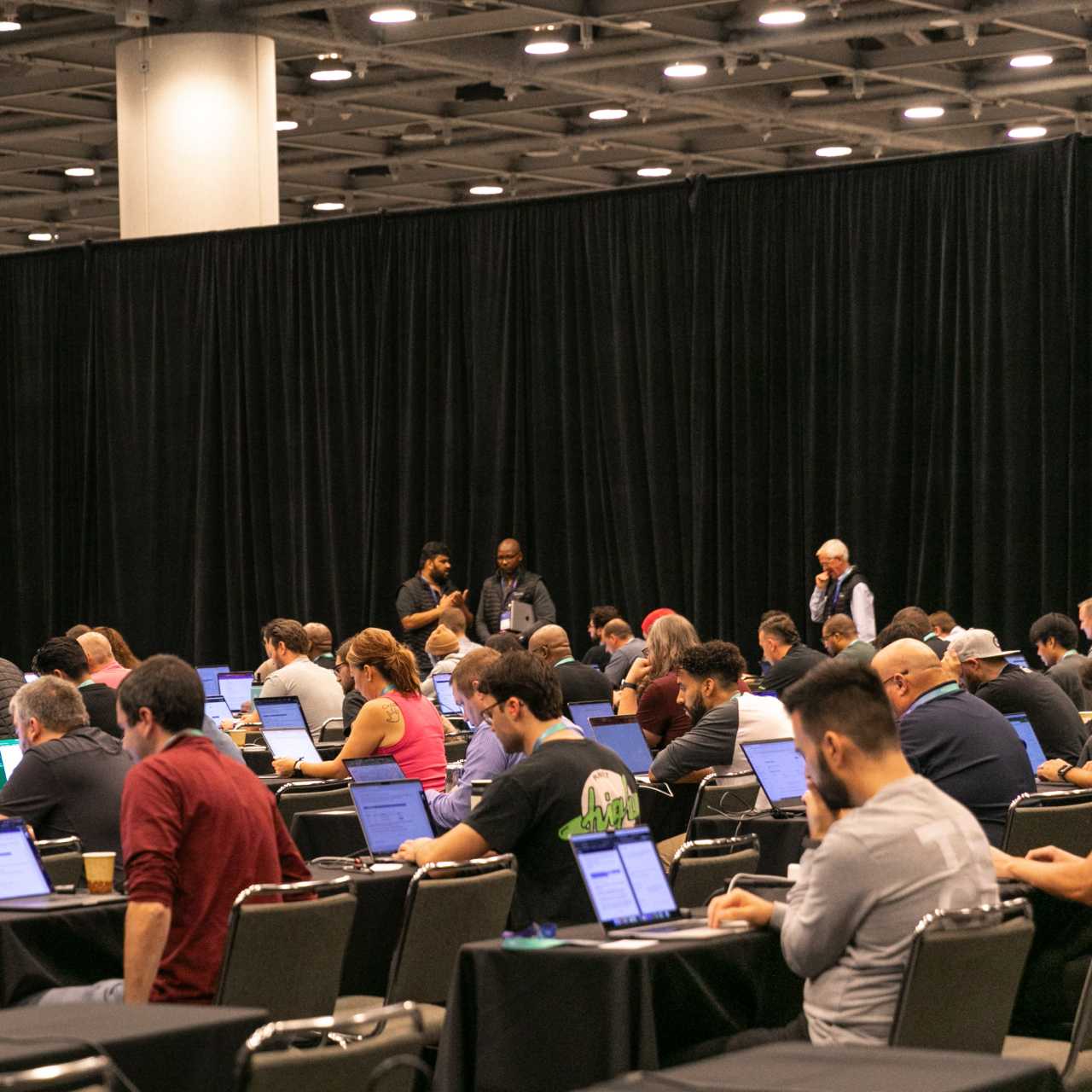 Photo of people sitting in a large auditorium at desks on laptops