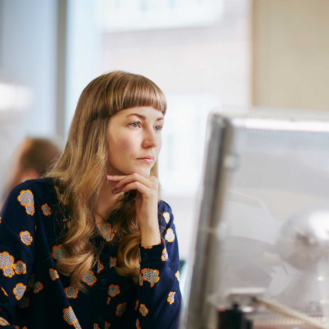 Woman sitting and starting at desktop computer