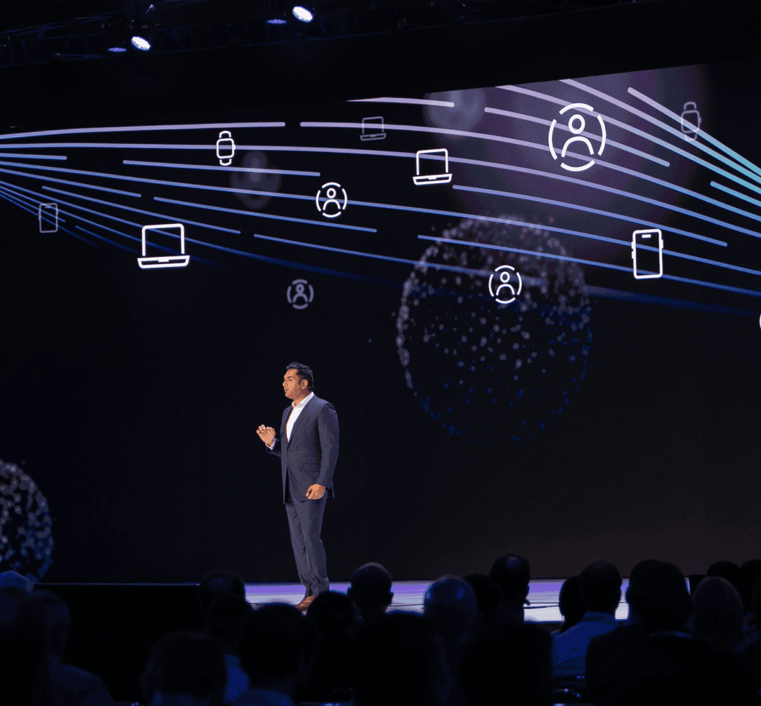 Image of a speaker standing on stage at a conference talking to the audience.