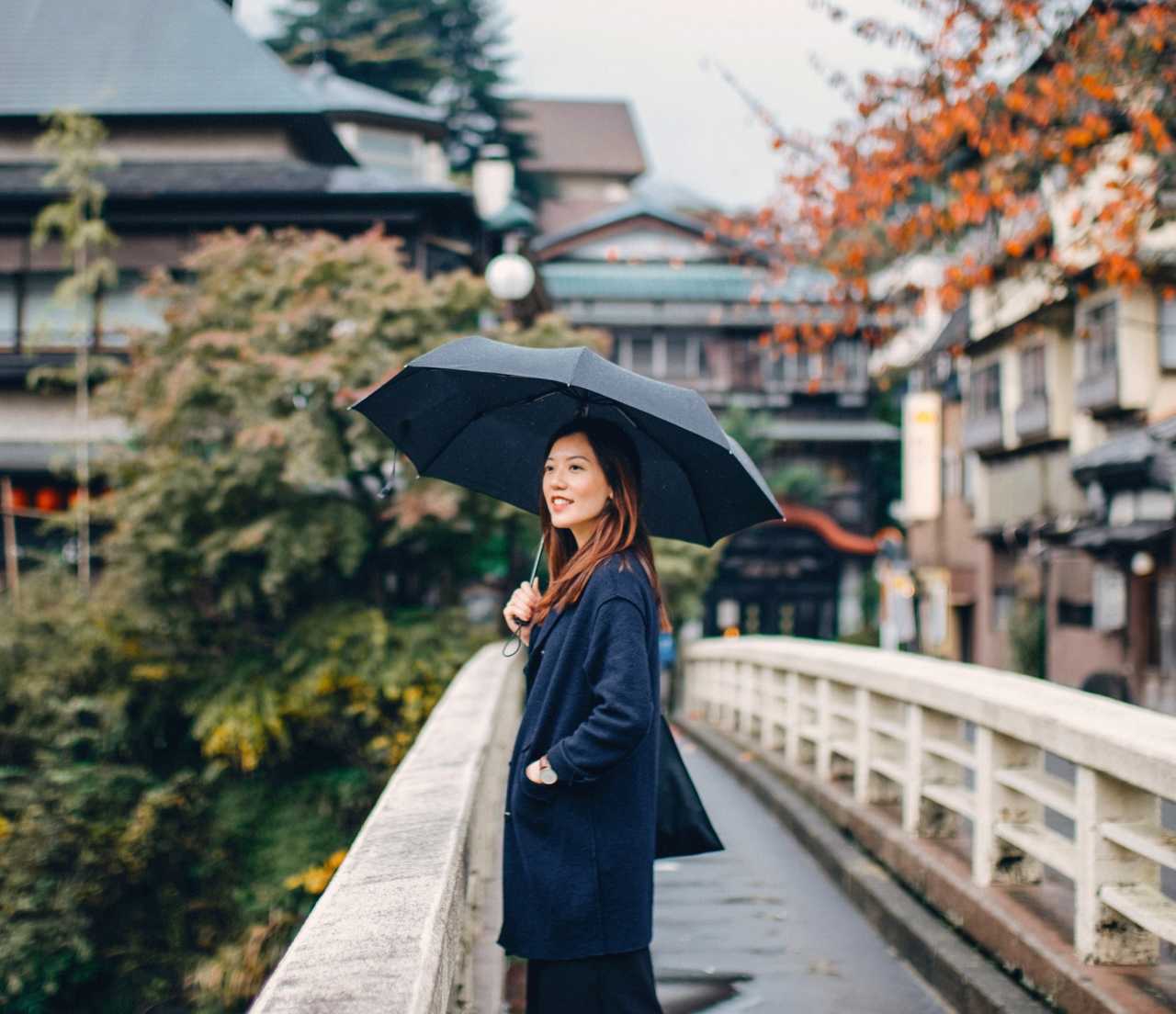 Woman standing on bridge while holding an umbrella