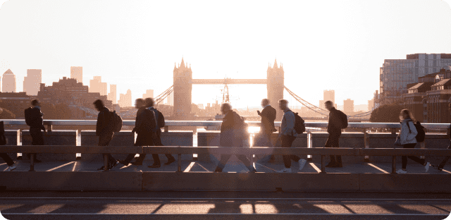 People walking across bridge during sunset