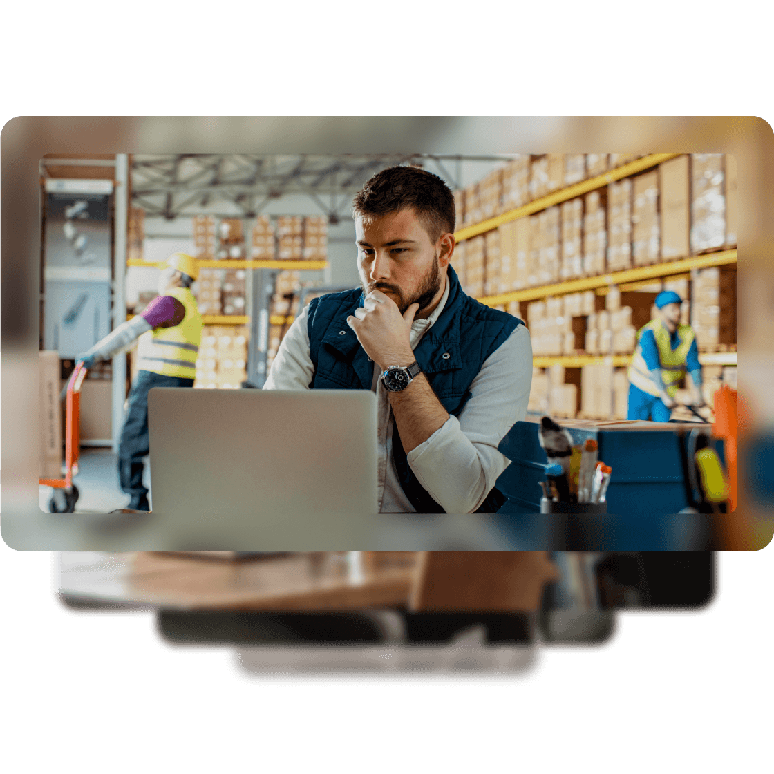 A man is working on his laptop while in a warehouse.