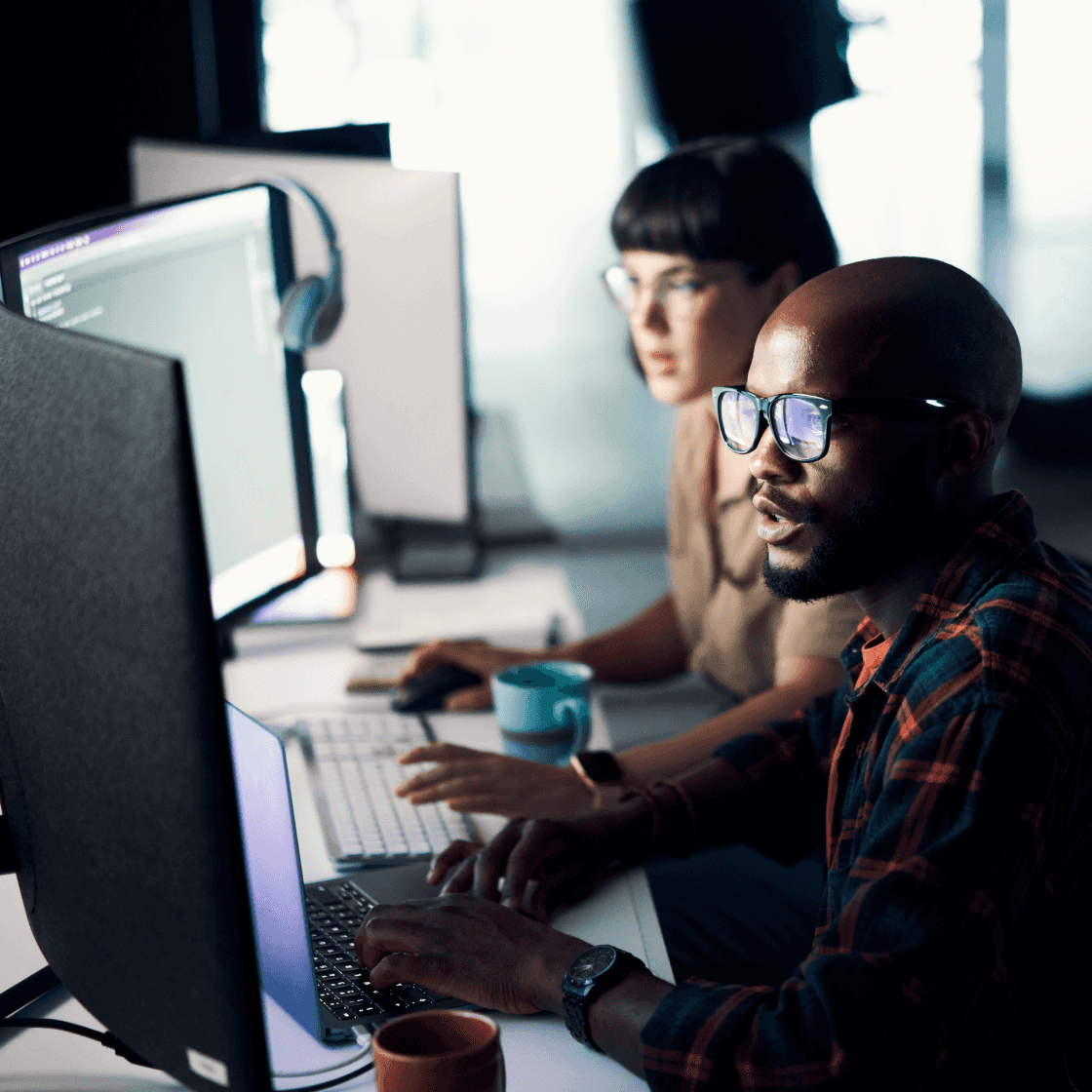 Two colleagues sitting at desks while working on their computers.