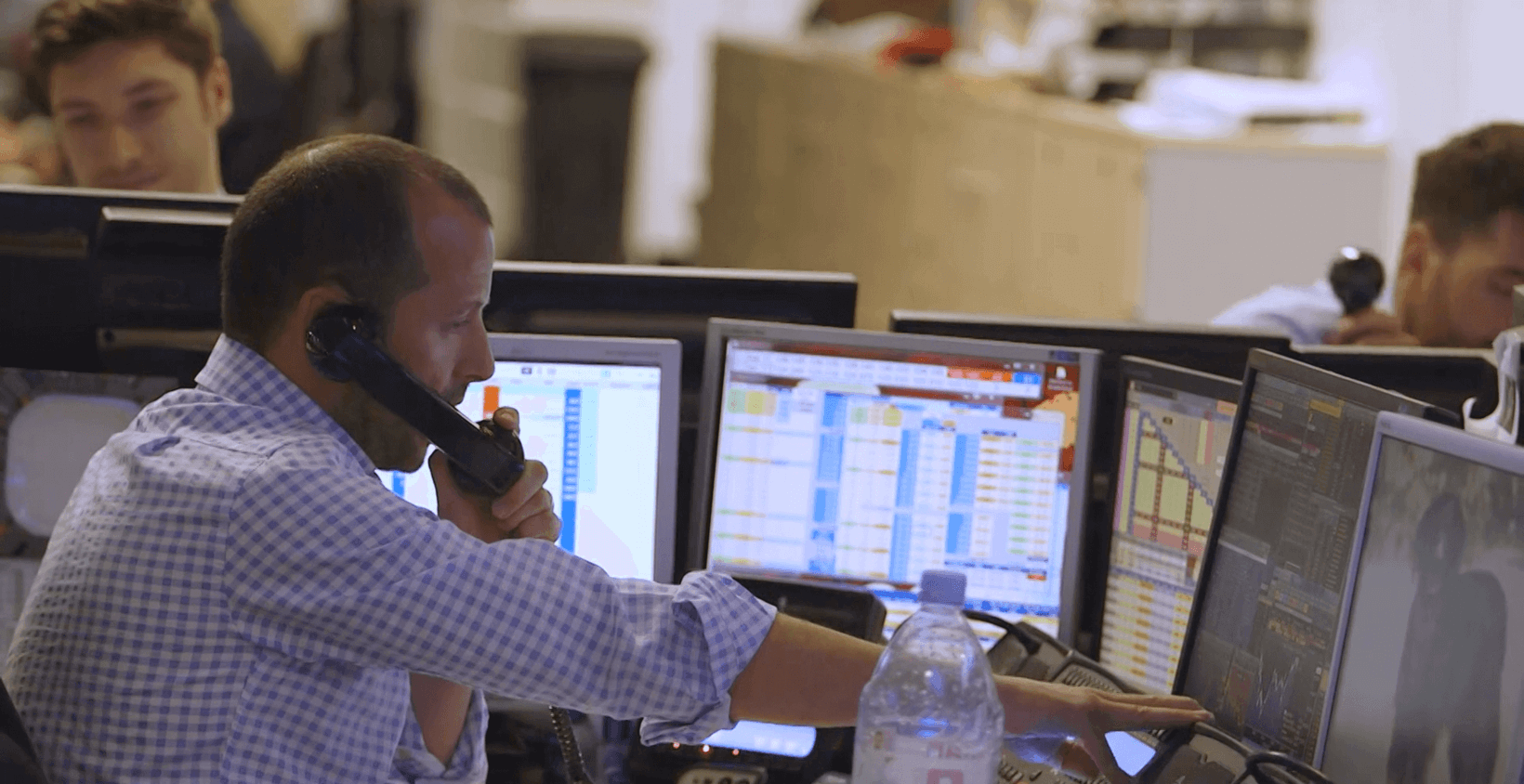 a man on phone call in front of the multiple monitors