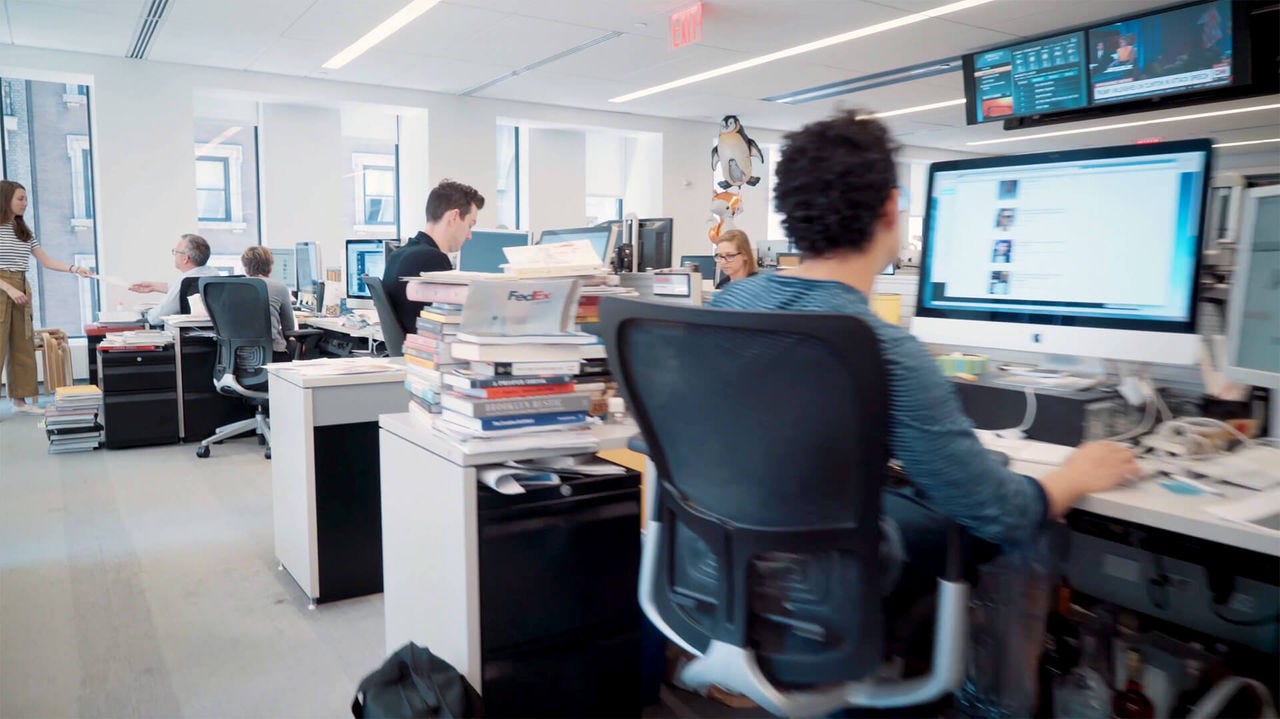 Image of an office showing a series of workstations during business hours.