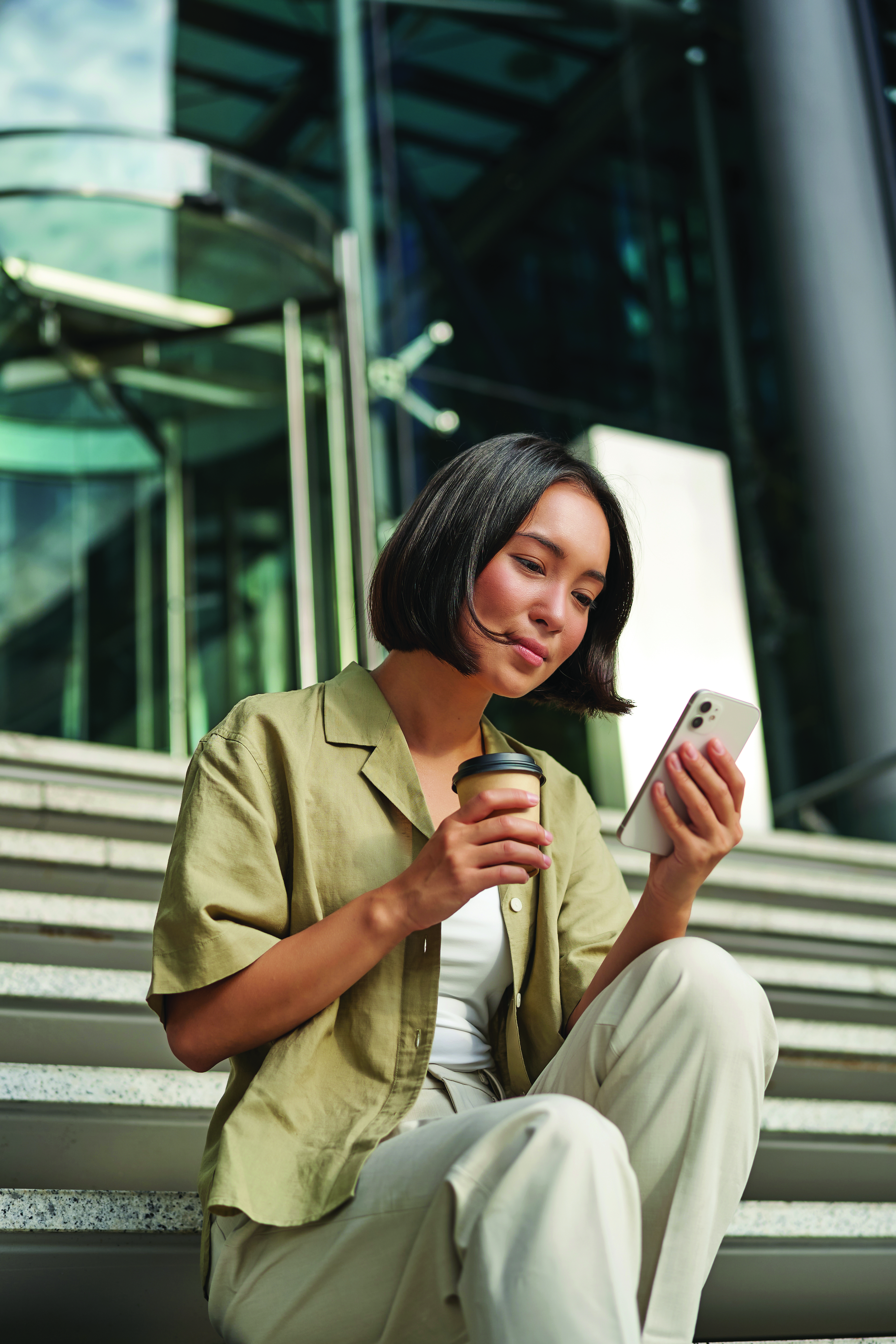 Woman looking at cell phone on office building steps