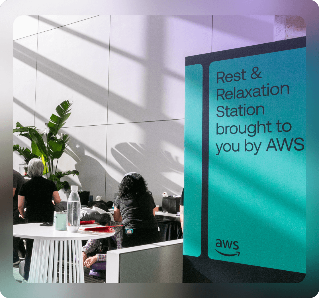 Large teal sign in Okta conference hall that says Rest & Relaxation Station brought to you by AWS.